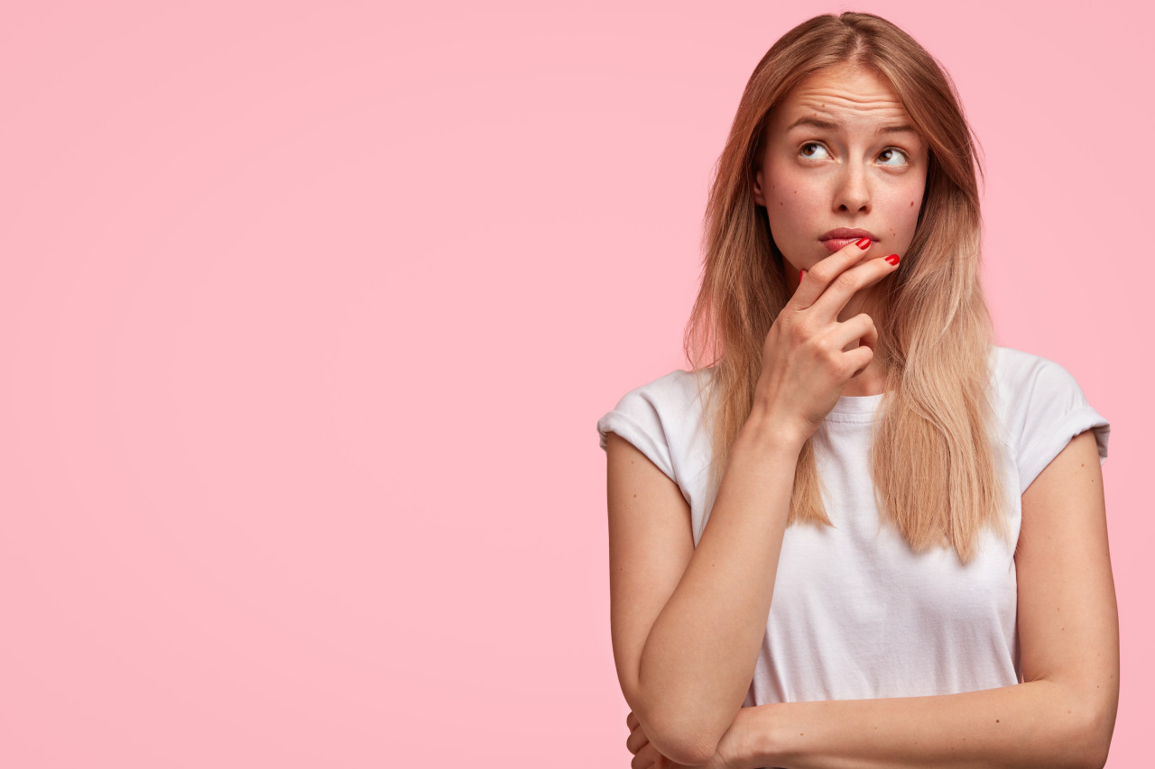 Woman thinking against a pink background