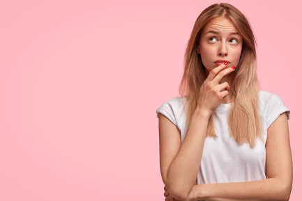 Woman thinking against a pink background